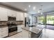 Modern kitchen with stainless steel appliances, granite countertops, a center island, and sliding glass doors at 19974 Bluebird Meadow Dr, Lutz, FL 33558