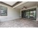 Covered patio with stone floor, view of back yard and sliding glass doors leading inside at 19974 Bluebird Meadow Dr, Lutz, FL 33558