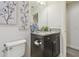 Elegant half bathroom featuring granite countertop, black vanity and decorative floral art at 21797 Briske Morning Ave, Land O Lakes, FL 34637