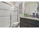 Modern bathroom with glass-enclosed shower, dark vanity cabinet and granite countertop and decorative artwork at 21797 Briske Morning Ave, Land O Lakes, FL 34637