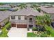 Stunning aerial view showcasing the home's stone facade, three-car garage, and meticulously landscaped front yard at 21797 Briske Morning Ave, Land O Lakes, FL 34637