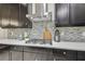 Modern kitchen counter with tile backsplash, cooktop, and stainless steel vent at 21797 Briske Morning Ave, Land O Lakes, FL 34637