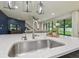 Close up of the kitchen sink, faucet, and white countertops; living room in the background at 21797 Briske Morning Ave, Land O Lakes, FL 34637