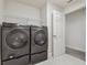 Modern laundry room features black washer and dryer with grey tile flooring at 21797 Briske Morning Ave, Land O Lakes, FL 34637