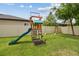 Backyard playground featuring a slide and swings set against a backdrop of a well-manicured lawn at 21797 Briske Morning Ave, Land O Lakes, FL 34637