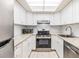 Renovated kitchen showcasing white cabinets, stainless steel appliances, and light granite countertops at 2699 Seville Blvd # 207, Clearwater, FL 33764