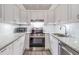 Modern kitchen boasting white cabinets, stainless steel appliances, and granite countertops at 2699 Seville Blvd # 207, Clearwater, FL 33764