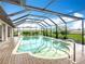 Relaxing screened-in pool area with brick pavers, spa, and view of the manicured lawn at 27466 Tierra Del Fuego Cir, Punta Gorda, FL 33983