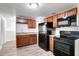 Modern kitchen featuring sleek black appliances, wood cabinetry, and stylish laminate flooring at 3204 Dodge St, Tampa, FL 33605