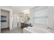 Bright bathroom featuring a soaking tub, walk-in shower, gray cabinets, sleek black fixtures, and tile floors at 32490 Tree Of Life Ave, Wesley Chapel, FL 33543