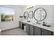 Bright bathroom featuring a double vanity with gray cabinets, sleek black fixtures, and a large sunny window at 32490 Tree Of Life Ave, Wesley Chapel, FL 33543