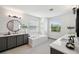 Bright bathroom featuring a double vanity with gray cabinets, sleek black fixtures, a soaking tub, and tile floors at 32490 Tree Of Life Ave, Wesley Chapel, FL 33543
