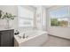 Bright bathroom featuring a soaking tub, gray cabinets, sleek black fixtures, and tile floors at 32490 Tree Of Life Ave, Wesley Chapel, FL 33543