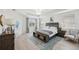 Bright bedroom with tray ceiling, light wood floors, and a blue accent rug and bench at the foot of the bed at 32490 Tree Of Life Ave, Wesley Chapel, FL 33543