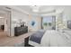 Bright bedroom with light wood floors, tray ceiling, and a blue accent rug and bench at the foot of the bed at 32490 Tree Of Life Ave, Wesley Chapel, FL 33543