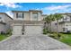 Two-story home with a gray exterior, a paver driveway, an attached three-car garage, and manicured landscaping at 32490 Tree Of Life Ave, Wesley Chapel, FL 33543