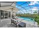 Screened in pool area with comfortable seating, an umbrella and a view of the beautiful surroundings at 32490 Tree Of Life Ave, Wesley Chapel, FL 33543