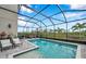 A sparkling screened-in pool area features comfortable seating and a tranquil view of nature at 32490 Tree Of Life Ave, Wesley Chapel, FL 33543
