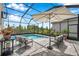 Screened in pool area with comfortable seating, an umbrella and a view of the beautiful surroundings at 32490 Tree Of Life Ave, Wesley Chapel, FL 33543