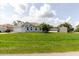 An inviting exterior view of a light blue single-story house with a lush green lawn and palm trees in the front yard at 4959 Cromey Rd, North Port, FL 34288