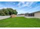 Backyard view of the shed with a privacy fence, green grass and cloudy skies at 5015 Summer Hill Dr, Zephyrhills, FL 33542