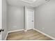 An empty room with light grey walls, a white ceiling, a door, and light brown laminate floors at 5015 Summer Hill Dr, Zephyrhills, FL 33542