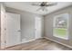 Bedroom with light gray walls, wood-look floors, ceiling fan and window with view to the yard at 5015 Summer Hill Dr, Zephyrhills, FL 33542