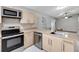 Bright kitchen features stainless steel appliances, light wood cabinetry, and eat-in counter with pendant lighting at 5015 Summer Hill Dr, Zephyrhills, FL 33542