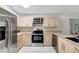 Bright kitchen features stainless steel appliances, light wood cabinetry, and eat-in counter with pendant lighting at 5015 Summer Hill Dr, Zephyrhills, FL 33542