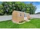 Backyard shed with double doors, windows and a small deck surrounded by green grass at 5015 Summer Hill Dr, Zephyrhills, FL 33542