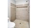 Walk-in shower with light stone-look tile, river rock floor, and built-in shelving at 5015 Summer Hill Dr, Zephyrhills, FL 33542