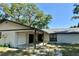 Single-story home showcasing a covered entry, one-car garage, and mature trees with a lush yard at 5614 Kenny Dr, Tampa, FL 33617