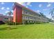 Three-story condo building with white facade, red accents, and landscaped green lawn and palm trees at 5728 14Th N Ave # 101B, St Petersburg, FL 33710