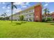 Three-story condo building with brick facade, white accents, and landscaped green lawn with palm trees at 5728 14Th N Ave # 101B, St Petersburg, FL 33710