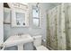Cozy bathroom featuring a pedestal sink, toilet, medicine cabinet, and a window with a shower with a floral curtain at 5961 36Th Ave N, St Petersburg, FL 33710