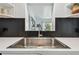 Close-up of a kitchen sink with modern fixtures, white countertops, and a stylish black backsplash at 5961 36Th Ave N, St Petersburg, FL 33710