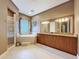 Well-lit bathroom featuring a double vanity, large mirror, walk-in shower, and soaking tub at 6204 Rockross Ave, New Port Richey, FL 34655