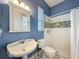 The bathroom is designed with blue walls, mosaic shower tiles, a white pedestal sink, and a toilet at 6204 Rockross Ave, New Port Richey, FL 34655