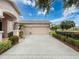 Attached two-car garage with a long concrete driveway, surrounded by manicured landscaping and lush greenery on a sunny day at 6204 Rockross Ave, New Port Richey, FL 34655