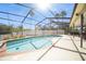 A screened in pool with clear blue water under a blue sky with palm tree views in the backyard at 6503 Santiago Ct, Apollo Beach, FL 33572