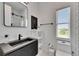 Modern bathroom with a black vanity, geometric mirror, and white shelving unit at 6512 Simone Shores Cir, Apollo Beach, FL 33572