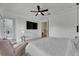 Bedroom with wood floors, a ceiling fan, chair and ottoman, flat screen TV, and ensuite bathroom at 6512 Simone Shores Cir, Apollo Beach, FL 33572