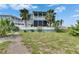 Beautiful two-story home showcases a backyard with lawn, palm trees, and white picket fence at 6512 Simone Shores Cir, Apollo Beach, FL 33572