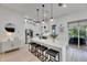 Modern white kitchen with stainless steel appliances, a large island with pendant lighting, and deck access at 6512 Simone Shores Cir, Apollo Beach, FL 33572