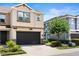 Lovely townhome showcasing a pristine dark two-car garage, and mature tree in the yard at 6711 Rocky Park St, Tampa, FL 33625