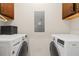 Bright laundry room features a pair of front-loading washing machines with cabinets overhead and utility panel at 7001 Interbay Blvd # 242, Tampa, FL 33616