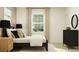 Relaxing bedroom featuring a dark-framed bed, complemented by neutral decor and natural light from the window at 9583 Runaway Breeze Dr, Land O Lakes, FL 34637