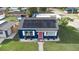 Aerial view of a blue home with solar panels, a pink door, and a well-maintained yard at 1001 57Th N Ave, St Petersburg, FL 33703