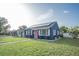 Charming blue home with solar panels, a pink door, white trim, and a green lawn at 1001 57Th N Ave, St Petersburg, FL 33703
