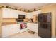 Compact kitchen with white cabinets, black appliances, and tile flooring at 1001 57Th N Ave, St Petersburg, FL 33703